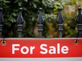 A file photo shows a real estate sign hanging on a fence in front of a house for sale in Ottawa.