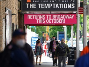 FILE PHOTO: People walk on the sidewalk past Broadway show marquees amid the coronavirus disease (COVID-19) pandemic in Manhattan, New York, U.S., May 13, 2021.