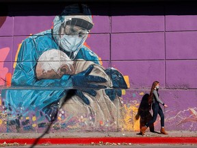 A woman walks past a graffitti depicting a healthcare worker embracing a man, during the coronavirus disease (COVID-19) pandemic, in Cordoba, Argentina, July 10, 2021.