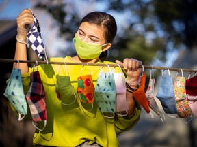 FILE: Yuni Cheng Wiik wears a protective face mask and gloves as she hangs in a rope protective face masks that she sewed at the girls's room of her home for friends and acquaintances as the outbreak of the coronavirus disease (COVID-19) continues, in Nesodden, Norway April 20, 2020. Picture taken April 20, 2020.