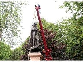 The statue of Sir John A Macdonald is taken off its pedestal in in City Park in Kingston on June 18, 2021.
