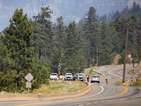 RCMP officers at a roadblock on the Trans-Canada Highway as wildfire burns in Lytton, B.C., on Friday, July 2, 2021.