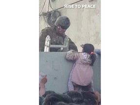 U.S. soldier stands guard while a girl tries to climb the wall as crowds gather near the wall at Kabul airport, Afghanistan August 17, 2021.