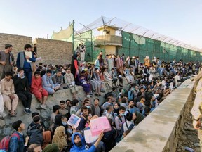 Scores of Afghani refugees wait outside Hamid Karzai International Airport in Kabul for departing flights.