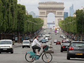 FILE: A cyclist wears a facemask as she crosses The Champs Elysees Avenue in Paris.