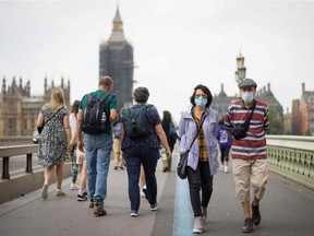 Pedestrians wearing face masks cross Westminster Bridge in central London on July 26, 2021.