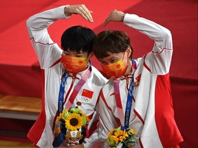 China's Bao Shanju (L) and Zhong Tianshi pose with their gold medals on the podium after the women's track cycling team sprint finals.