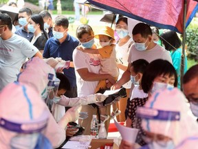 Residents queue to take nucleic acid tests for the coronavirus in Wuhan in China's central Hubei province on August 3, 2021, as the city tests its entire population for Covid-19.