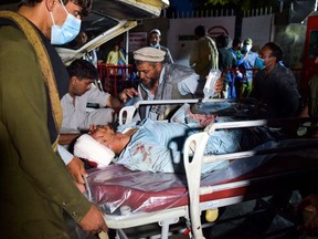 EDITORS NOTE: Graphic content / Medical and hospital staff bring an injured man on a stretcher for treatment after two blasts, which killed at least five and wounded a dozen, outside the airport in Kabul on August 26, 2021.