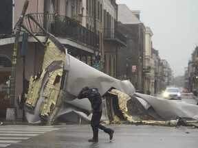 A man passes by a section of roof that was blown off of a building in the French Quarter by Hurricane Ida winds, Sunday, Aug. 29, 2021, in New Orleans.