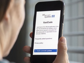 A woman looks at the Quebec government's new vaccine passport called VaxiCode on a phone in Montreal, Wednesday, August 25, 2021, as the COVID-19 pandemic continues in Canada and around the world.