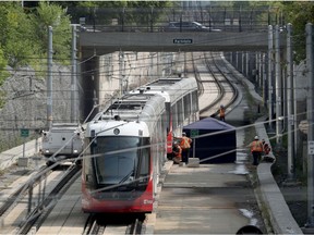 Maintenance crews work on an O-train stopped at Tunney's Pasture station Monday. The train has been stuck there since Sunday after one of its axles derailed.