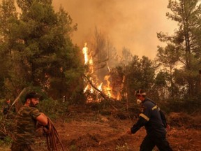 Firefighters and volunteers try to extinguish a wildfire burning in the village of Galatsona, on the island of Evia, Greece, August 9, 2021.