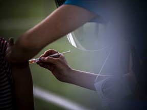 A health-care worker administers a COVID vaccine.