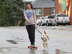 Neenah the dog pulls Christopher Rainville on his skateboard under cloudy skies.