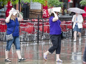 Visitors to the Byward Market retreat under brochures and umbrellas as the recent warm temperatures give way to cloudy skies and periods of rain.