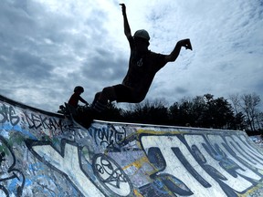 Riding the rim of a bowl at the Centrepointe skate park under some. cloudy skies and cooler temperatures.