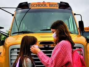 Two students assist each other wearing facemasks.