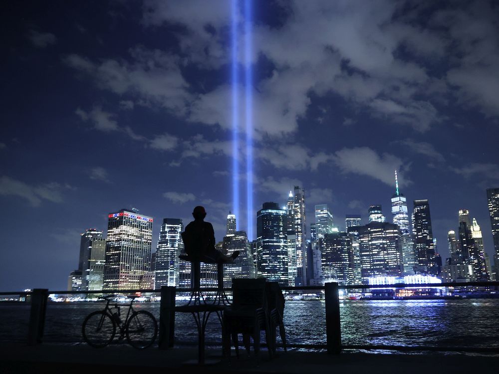 A person watches the Tribute In Light shine into the sky from Lower Manhattan during a test on September 07, 2021 in New York City. 
