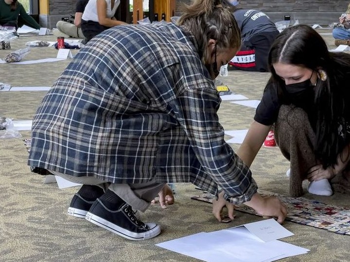  Volunteers arrange some of the 57,000 hand painted tiles, laid out in a memory labyrinth in preparation for September 30, 2021.