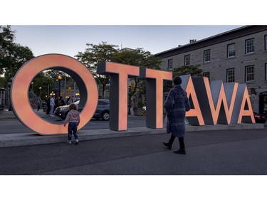 A woman and child walk towards the OTTAWA sign in the ByWard Market that was illuminated in orange on the inaugural National Day for Truth and Reconciliation.