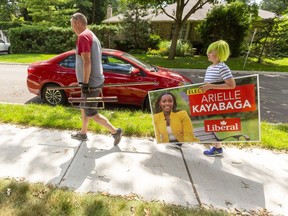 Mike Cairns, a longtime liberal volunteer and his son, Jackson Cairns, 11 tote signs for London West Liberal MP candidate Arielle Kayabaga in London, Ont. Mike Hensen/Postmedia Network