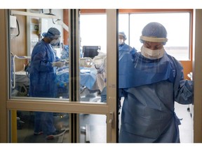 A nurse re-assigned to the Intensive Care Unit stands in a doorway after helping to intubate a patient suffering from COVID-19.