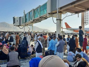 In this file photo, Afghans crowd the tarmac of the Kabul airport on Aug. 16, 2021, trying to flee the country as the Taliban take control.
