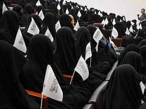 Veiled students hold Taliban flags as they listen to female speakers at a rally at the Shaheed Rabbani Education University in Kabul on September 11, 2021.
