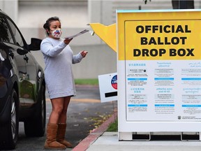 A woman steps out of her vehicle to drop off her ballot into an official ballot drop box outside the Los Angeles County Registrar's Office in Norwalk, California on September 14, 2021 in the recall election of California Governor Gavin Newsom.