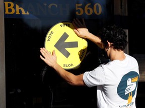 Information officer at a polling station Rody Yehia adjusts a sign during Canada's federal election, in Kingston, Ontario, Canada September 20, 2021.