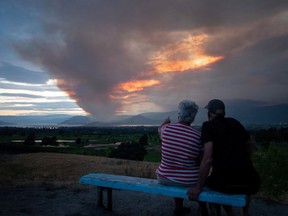 A couple view the Mount Law wildfire, near Peachland and Glenrosa on the west side of Okanagan Lake, from the waterfront in Kelowna, British Columbia, Canada August 15, 2021.