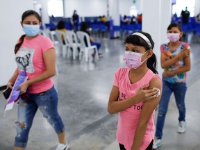 Twins walk with their mother after receiving their first dose of the Sinopharm COVID-19 vaccine at Hospital El Salvador vaccination center in San Salvador, September 23, 2021. COVID-19 vaccines have not been approved yet in Canada.