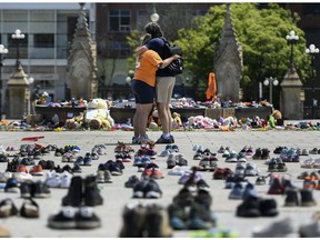 Two people embrace in front of the Centennial Flame on Parliament Hill in June, at a memorial for the 215 children whose remains were found at the grounds of the former Kamloops Indian Residential School at Tk'emlups te Secwépemc First Nation in Kamloops, B.C.