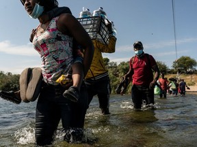 Migrants seeking asylum in the U.S. walk in the Rio Grande river near the International Bridge between Mexico and the U.S. as they wait to be processed, in Del Rio, Texas, U.S., September 16, 2021. According to officials, some migrants cross back and forth into Mexico to buy food and supplies.