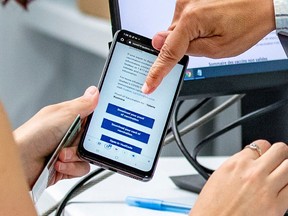 CIUSSS West-Central employee Mohamed Imhidi helps Valerie Kuzmina create her vaccine passport at the vaccination clinic at Decarie Square in Montreal Monday August 30, 2021.