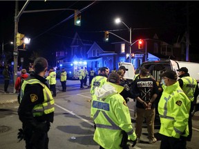 Police place a man in a prisoner transport van after a disturbance at the intersection of Johnson Street and University Avenue Saturday as thousands of students celebrated Queen's University homecoming in Kingston, Ont. on Saturday, Oct. 16, 2021.