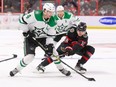 Miro Heiskanen #4 of the Dallas Stars battles for the puck with Tim Stuetzle #18 of the Ottawa Senators.