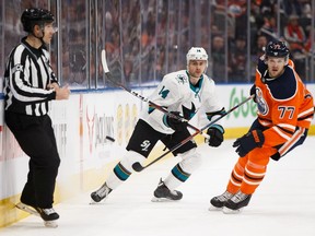 Edmonton Oilers' Oscar Klefbom (77) and San Jose Sharks' Dylan Gambrell (14) watch a flying puck during the second period of a NHL game at Rogers Place in Edmonton, on Saturday, Feb. 9, 2019.