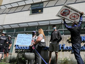 Protesters hold signs during an anti-vaccine mandate protest outside Toronto General Hospital in Toronto, Ontario, Canada September 13, 2021.