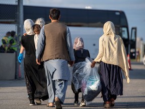 Afghan refugees who supported Canada's mission in Afghanistan prepare to board buses after arriving in Canada, at Toronto Pearson International Airport August 24, 2021.