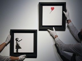 Art handlers Becky and Adam view "Girl With Balloon" diptych by British artist Banksy, which forms part of the upcoming auction on October 15 at Christie's, "20th/21st Century: Evening Sale Including Thinking Italian,"in London, Britain, October 1, 2021.