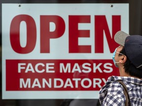 Files: A sign advises that masks are mandatory in a business in Toronto.