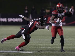 Stampeders running back Ka'Deem Carey evades a tackle by Redblacks linebacker Micah Awe as he runs with the ball during the first half of Friday's game.
