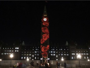 File: People visit Parliament Hill as poppies are projected on the Peace Tower