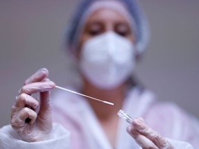 A worker holds a test tube after administering a nasal swab to a patient at a coronavirus disease (COVID-19) testing centre.