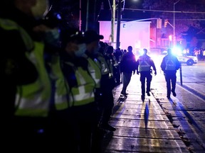 A skateboarder passes a line of OPP officers along Brock Street after a gathering of students in Victoria Park was declared an aggravated nuisance party and cleared out by police on Saturday.