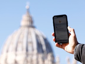A man shows the 'Click to Pray' app, a smartphone app designed to allow the faithful to pray with a click, near St. Peter's Square at the Vatican, October 19, 2021.