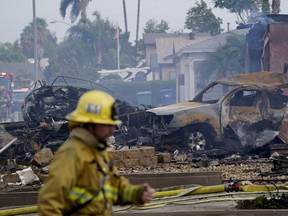 Fire crews work the scene of a small plane crash, Monday, Oct. 11, 2021, in Santee, Calif. At least two people were killed and two others were injured when the plane crashed into a suburban Southern California neighborhood, setting two homes ablaze, authorities said.