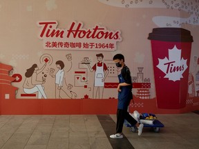 A man walks past a store front poster advertising the opening of a cafe of the Canadian coffee and fast food chain Tim Hortons in Beijing, China, July 6, 2020.